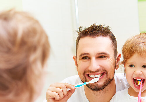 Happy family father and child girl brushing her teeth in bathroom toothbrushes