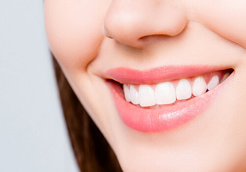 Close up portrait of beautiful wide smile with whitening teeth of young fresh woman isolated over white background, dental care