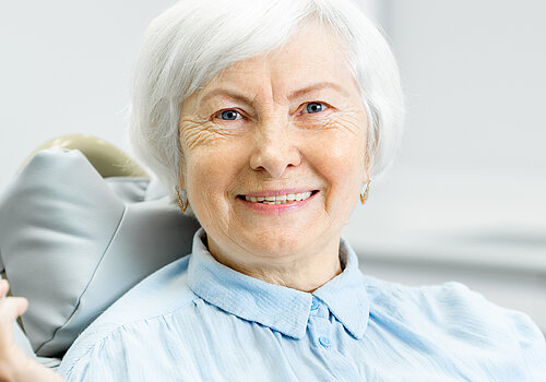 Portrait of a beautiful senior woman with healthy smile holding green apple at the dental office