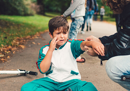 Father caring about his son after an accident with push scooter outside